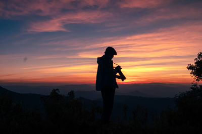 Silhouette man standing against orange sky during sunset