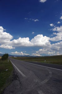 Road by agricultural field against sky