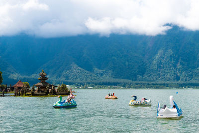 People on boat in river against mountains