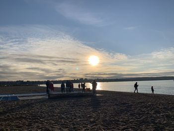 People on beach against sky during sunset