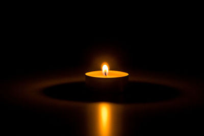 Close-up of lit candle in the dark