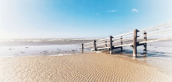 Wooden posts on beach against clear sky