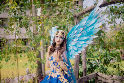 Portrait of young woman standing against plants