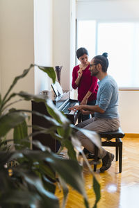 Man and woman using piano at home