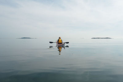 Rear view of man kayaking on sea against sky