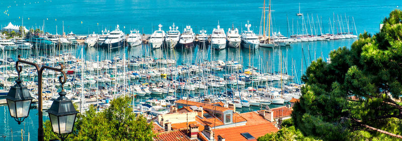 High angle view of sailboats moored in sea against buildings in city