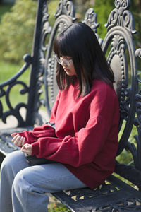 Portrait of asian teenager wearing eyeglasses sitting on bench