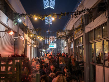 People on illuminated street amidst buildings at night