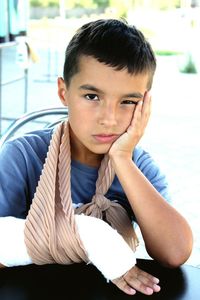 Portrait of boy with plaster cast on arm sitting at table