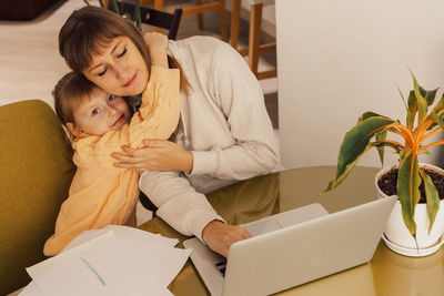 Working mom works from home office with kid. woman using laptop. child drawing. woman freelancer