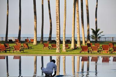 Rear view of man swimming in pool against lake