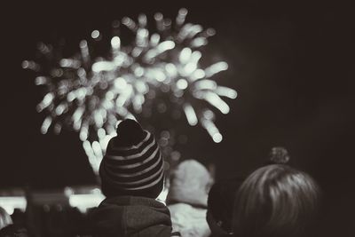 Rear view of people watching firecracker at night