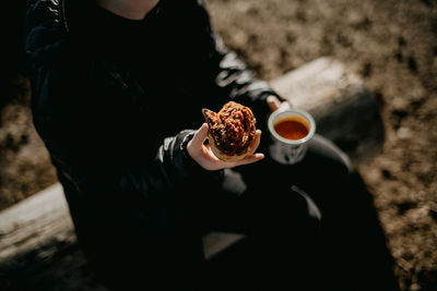 Midsection of girl holding food sitting outdoors