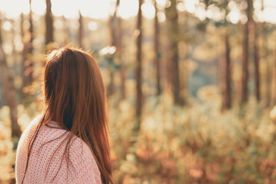 Rear view of woman standing against trees