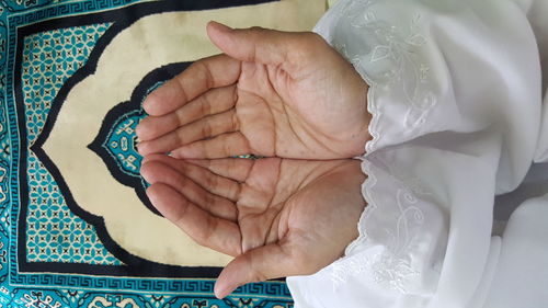 High angle view of cupped hands praying on textile