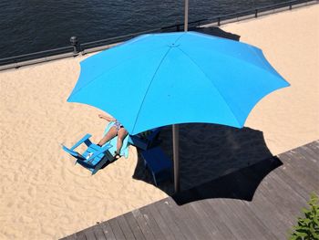 Low section of woman sitting on chair at beach