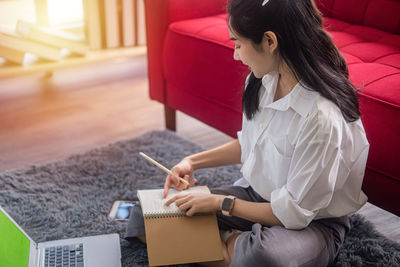 Woman using phone while sitting on laptop