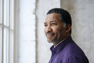 Thoughtful mature man looking out through window