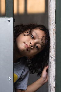 Close-up portrait of boy peeking through door at home