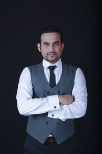 Portrait of smiling young man against black background