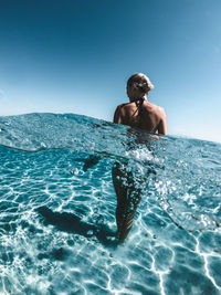 Rear view of shirtless man swimming in sea