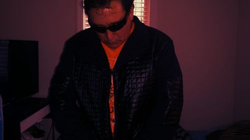 Close-up of man wearing leather jacket and sunglasses at home