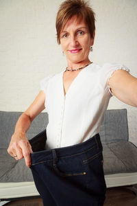 Portrait of smiling woman standing against wall