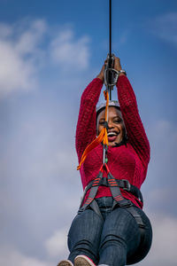 Low angle view of woman holding rope against sky