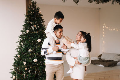 Multi-racial family with two children celebrate the christmas holiday in a decorated indoor house