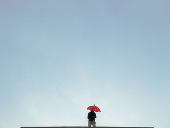 A person standing alone with an umbrella on the rooftop