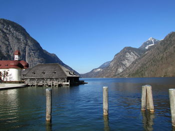 Wooden posts in lake against blue sky