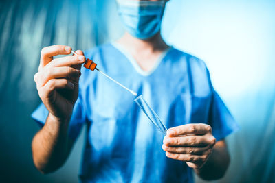 Close-up of man holding cigarette against blue background