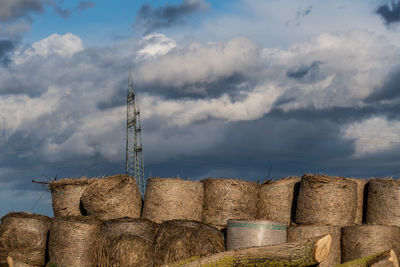 Stack of hay bales on field against sky