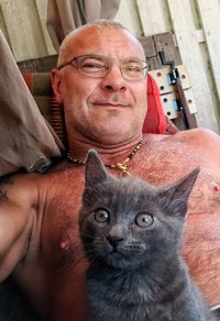 Portrait of shirtless mature man with cat resting at home