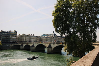 Arch bridge over river in city against sky