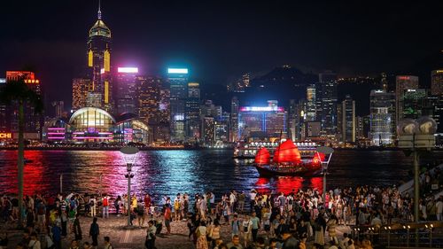 Crowd at harbor in illuminated city during night