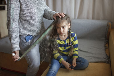 Midsection of mother combing daughters hair