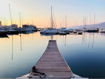 Sailboats moored at harbor against clear sky