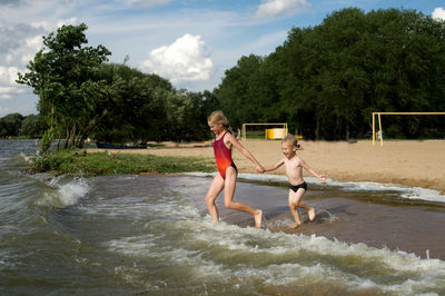 A boy and a girl run along the beach into the sea