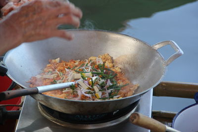 Close-up of person preparing food in cooking pan