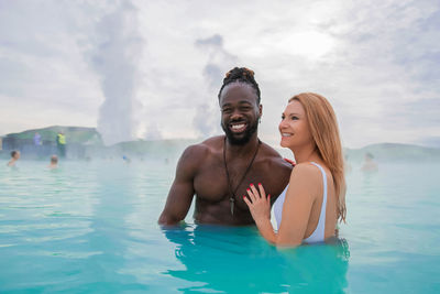 Happy couple standing in hot spring