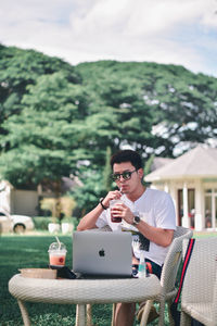 Young man using mobile phone while sitting on table