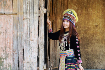 Smiling woman in traditional clothing standing against wall