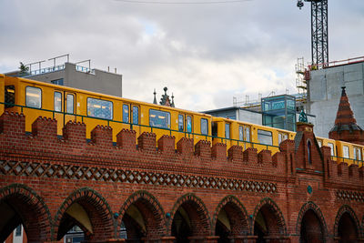 Yellow train travels across a historic red brick bridge in berlin