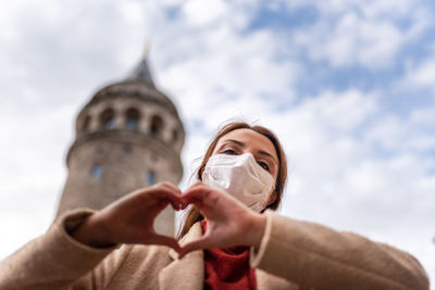 Low angle view of woman holding umbrella against sky