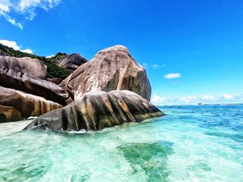 Scenic view of rocks in sea against blue sky