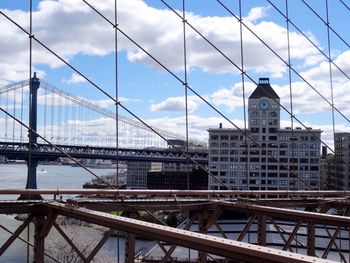 Suspension bridge in city against sky