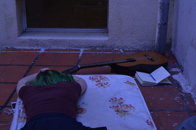 Rear view of woman lying down by guitar