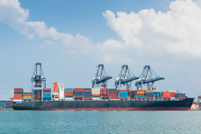 Cranes at commercial dock against sky