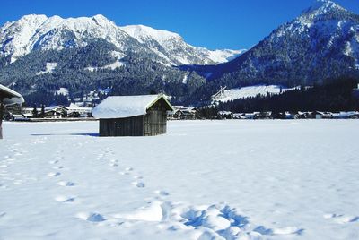 Snow covered landscape and houses against mountains